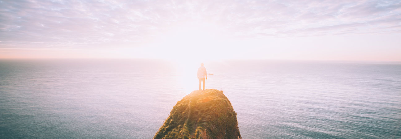 Hombre en una montaña mirando al mar