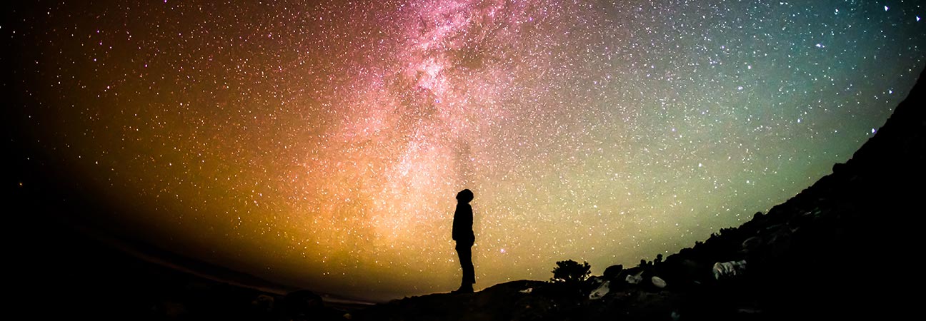 Hombre mirando a cielo lleno de estrellas